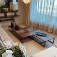 Load image into Gallery viewer, A modern coffee table with a minimalist metal base and a wooden surface featuring a unique curved detail in a living room setting.