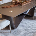 Load image into Gallery viewer, A modern dining table with a unique infinity symbol shaped base and a glass tabletop.