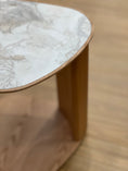 Load image into Gallery viewer, Close-up of a marble-top side table with wooden legs on a wooden floor.