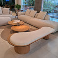 Load image into Gallery viewer, Modern living room with beige sectional sofa, wooden coffee table, and large windows.