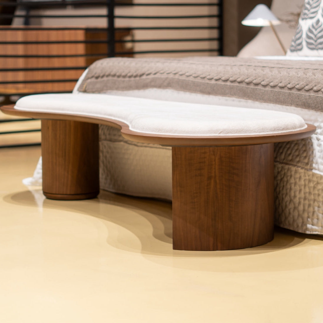Wooden bench with a white cushion in a bedroom setting