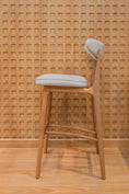 Load image into Gallery viewer, Wooden bar stool with a white cushion against a textured wooden wall.