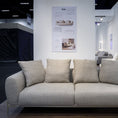 Load image into Gallery viewer, Gray sofa in a showroom with posters on the wall.