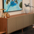 Charger l'image dans la visionneuse de la galerie, A mid-century modern sideboard cabinet with a textured geometric patterned front, styled in a room setting under a framed abstract painting.