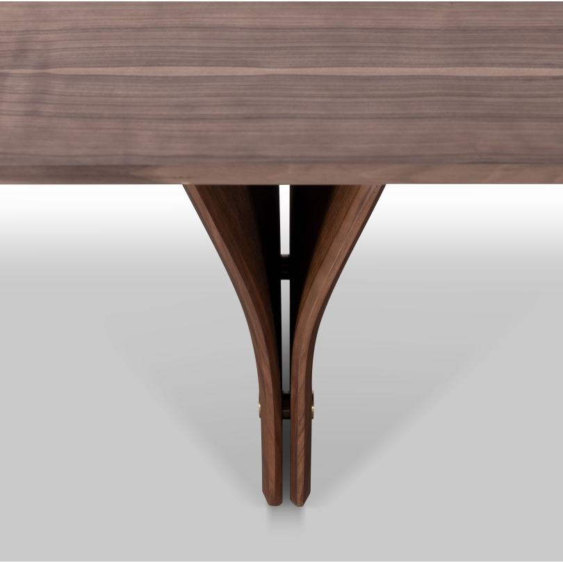 A rectangular dining table leg detail showing natural walnut wood finish and a distinctive Y-shaped design in its legs, set against a white background.
