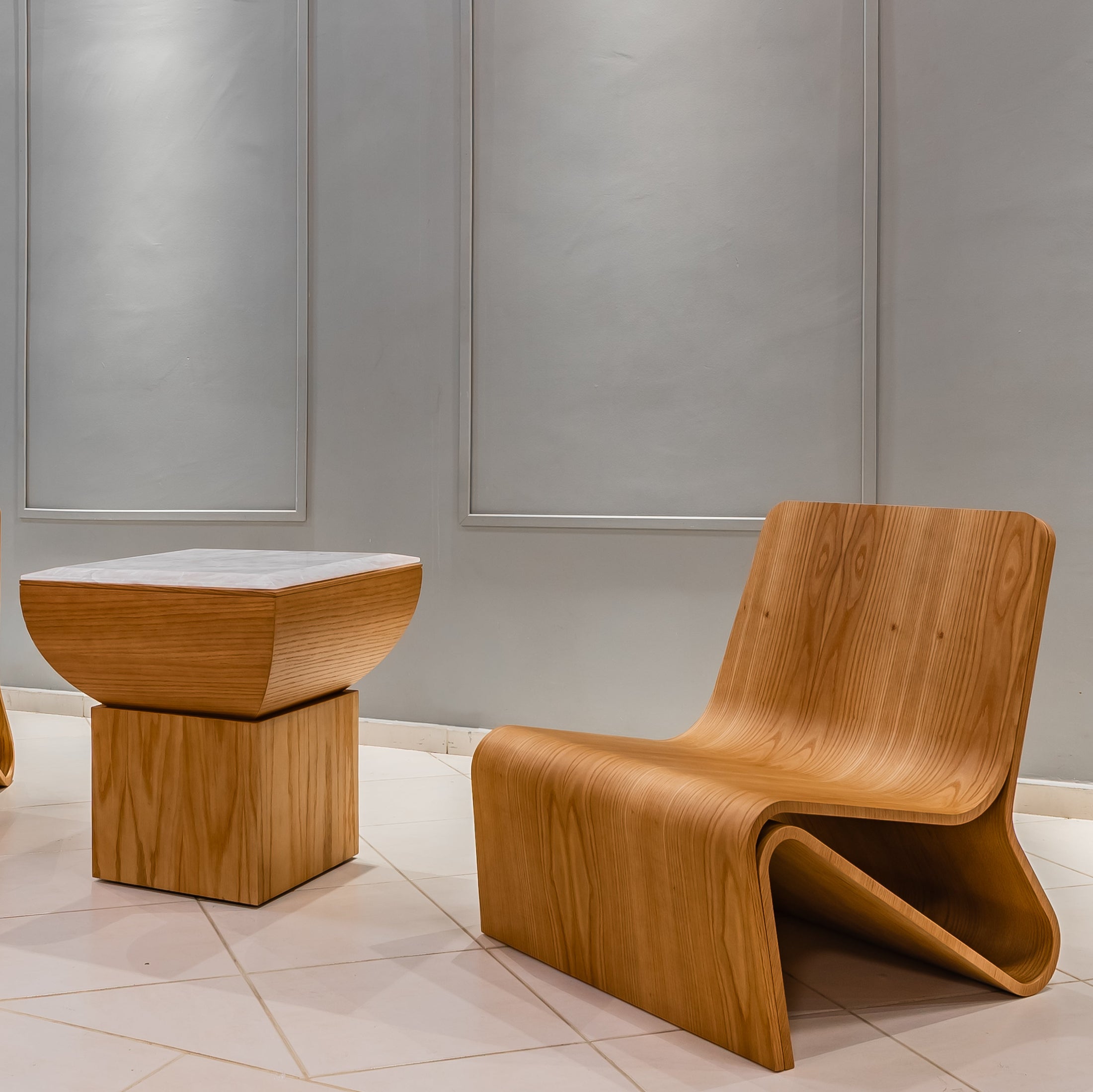 Modern wooden chairs and table against a gray wall.