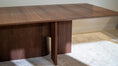 Load image into Gallery viewer, Wooden dining table with a modern design in a room with light-colored carpet and wall.