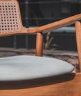 Load image into Gallery viewer, Wooden chair with a gray cushion on a blurred outdoor background