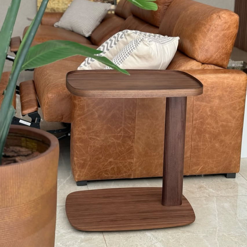 A rectangular brown side table with a wooden leg and base, and a dark fabric top.