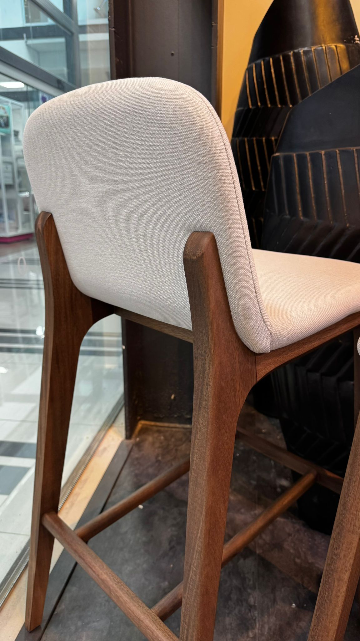 Bar stool with white cushioned seat and backrest in a modern setting