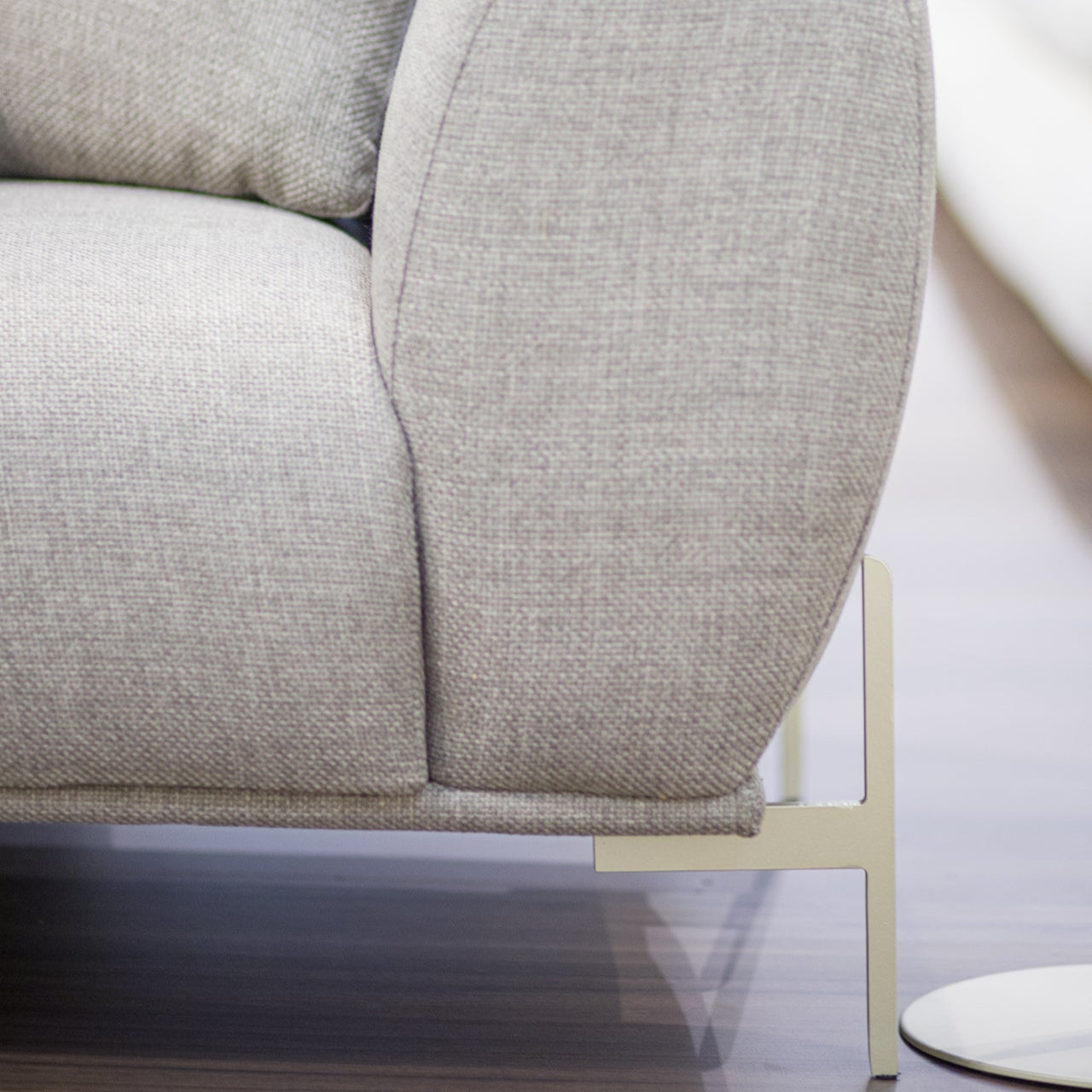 Gray upholstered sofa with a metallic base on a wood surface.