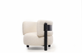 Charger l'image dans la visionneuse de la galerie, A modern low-profile armchair upholstered in cream bouclé fabric with a black side panel and black legs, shown against a plain white background.