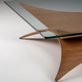 Load image into Gallery viewer, Close-up of a modern wooden table base with a clear glass tabletop, showing the natural wood grain and curved triangular support structure on a light gray studio background.