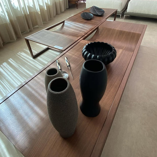 A modern coffee table with a minimalist metal base and a wooden surface featuring a unique curved detail.