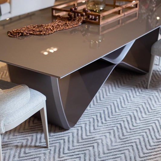 A modern dining table with a unique infinity symbol shaped base and a glass tabletop.
