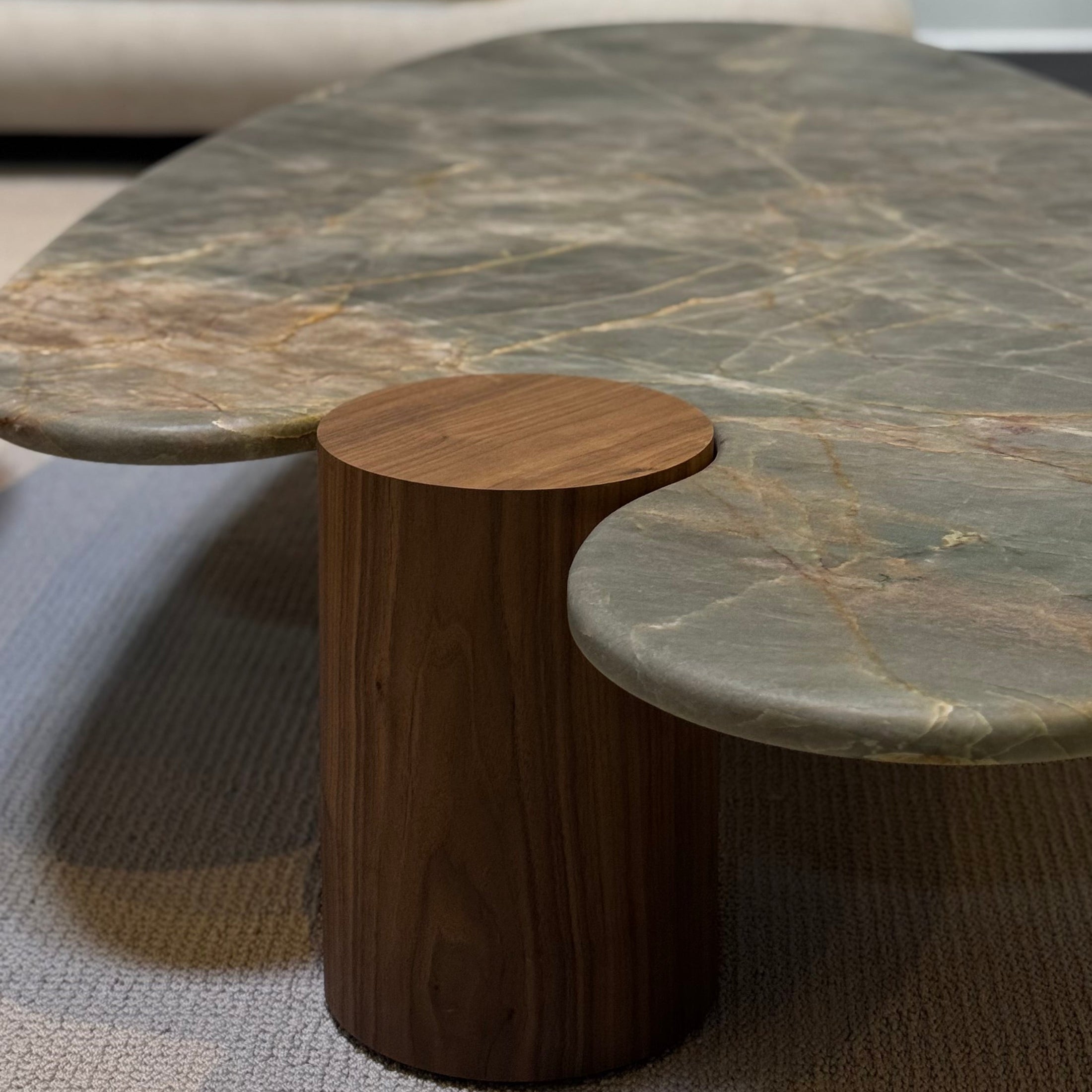 Round marble coffee table with wooden base in a living room setting