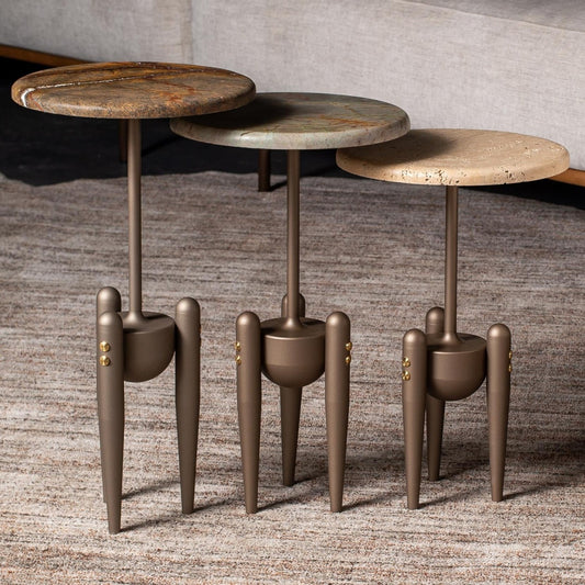 Three round side tables with unique legs on a textured floor.