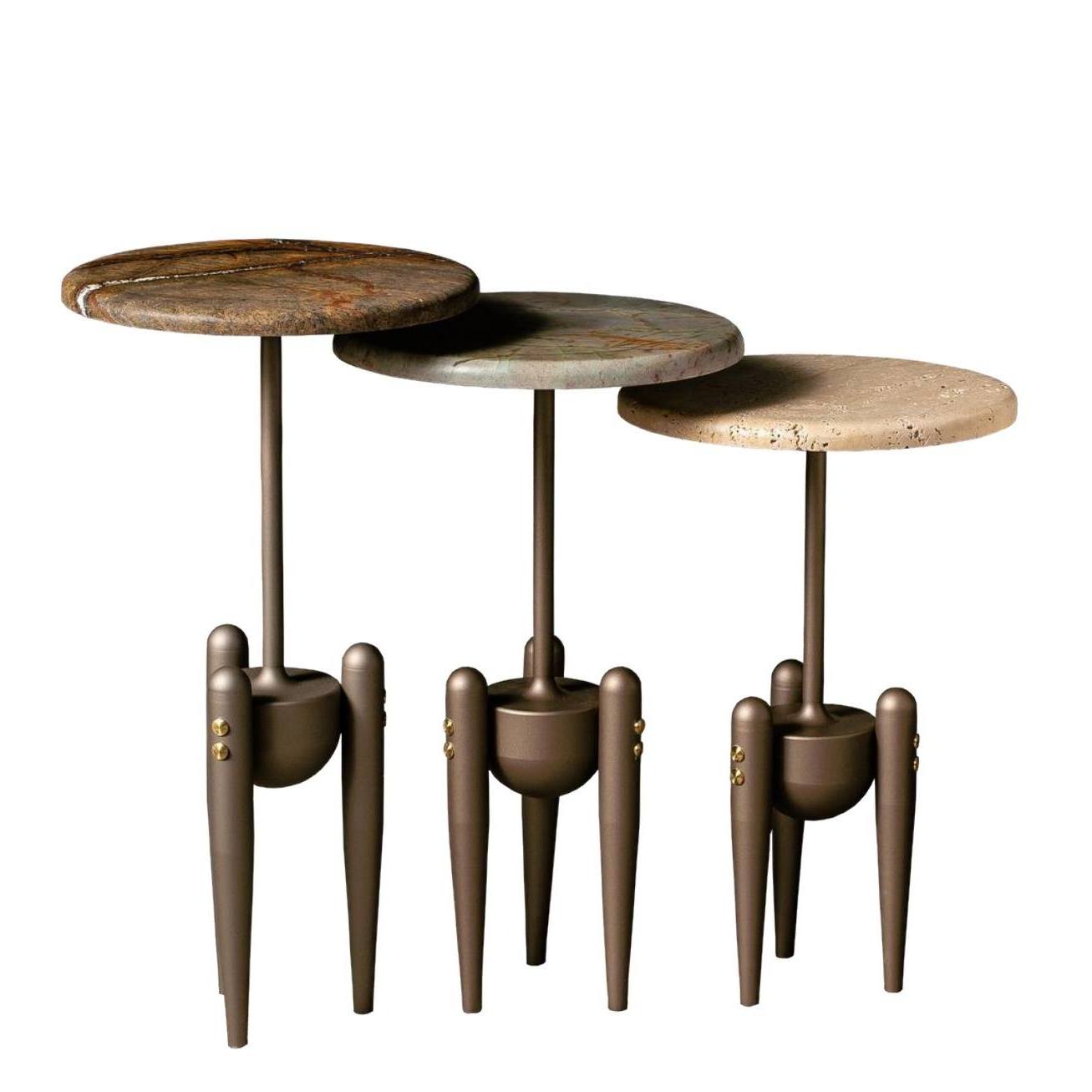 Set of three round side tables with unique legs on a white background