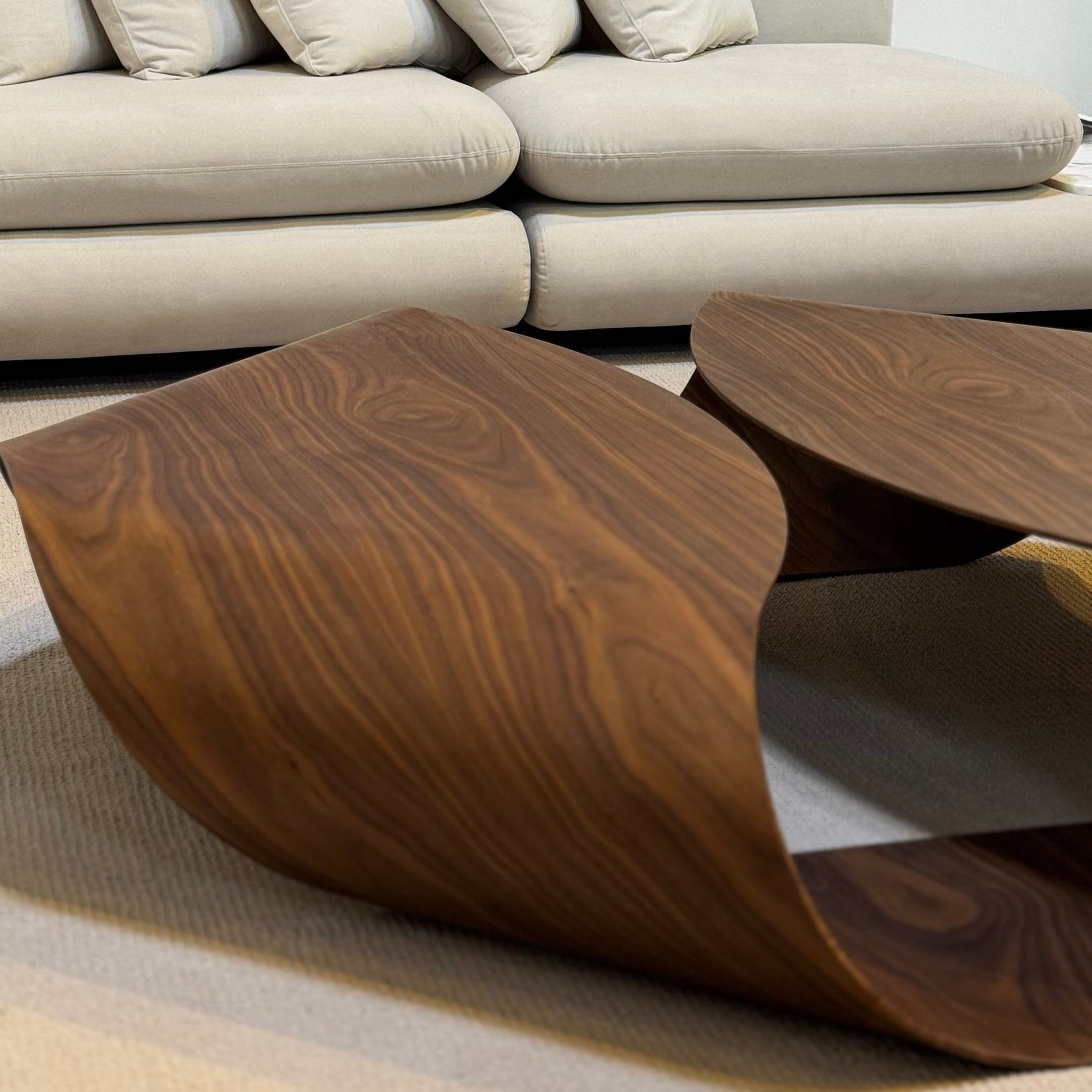 Modern living room with a beige sofa, wooden coffee table, and abstract blue artwork.