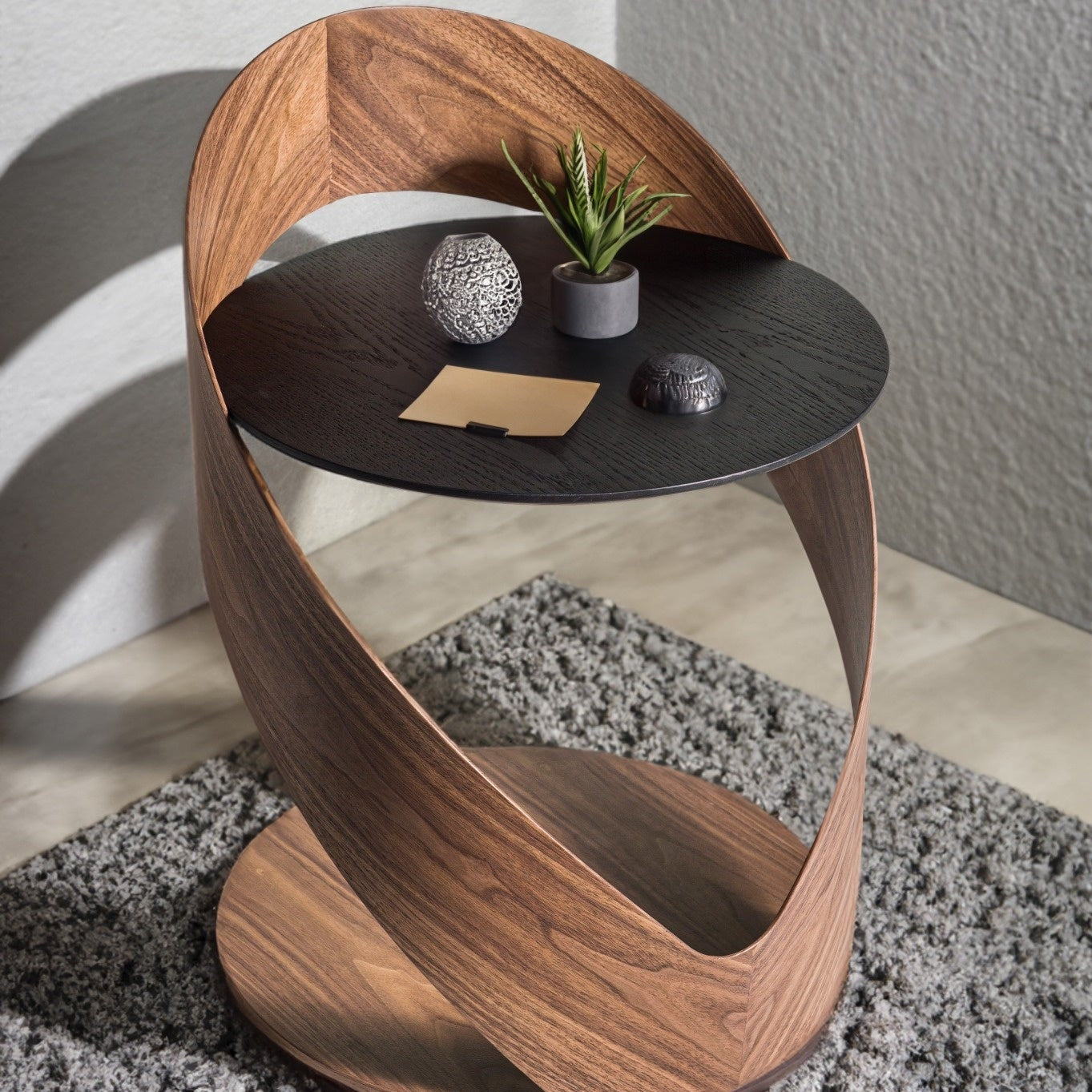 Modern side table with wooden base and black top, featuring decorative items.