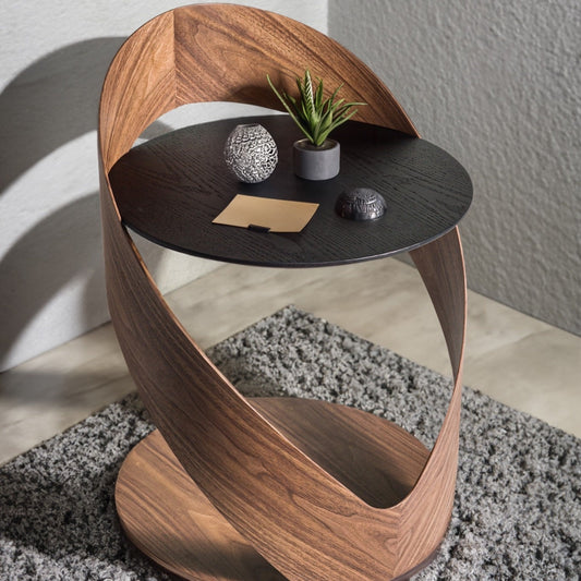 Modern side table with wooden base and black top, featuring decorative items.