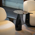 Charger l'image dans la visionneuse de la galerie, A modern black side table with a glossy tapered pedestal base, positioned between two cream-colored upholstered armchairs in a contemporary interior setting.
