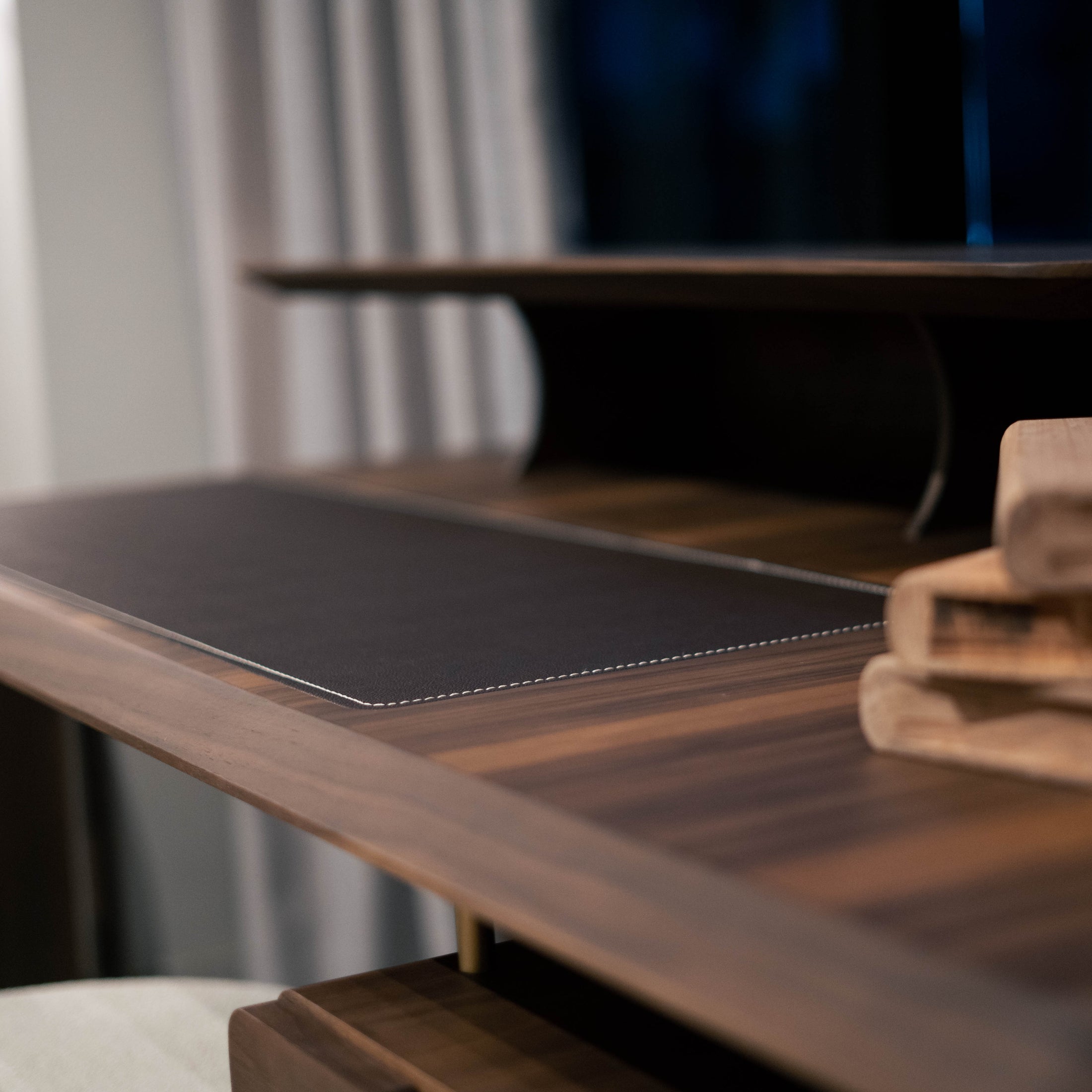 Wooden desk with a mouse pad and books in a blurred indoor setting
