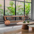 Load image into Gallery viewer, Modern indoor setting with wooden bar cart, tables and plants near large windows.
