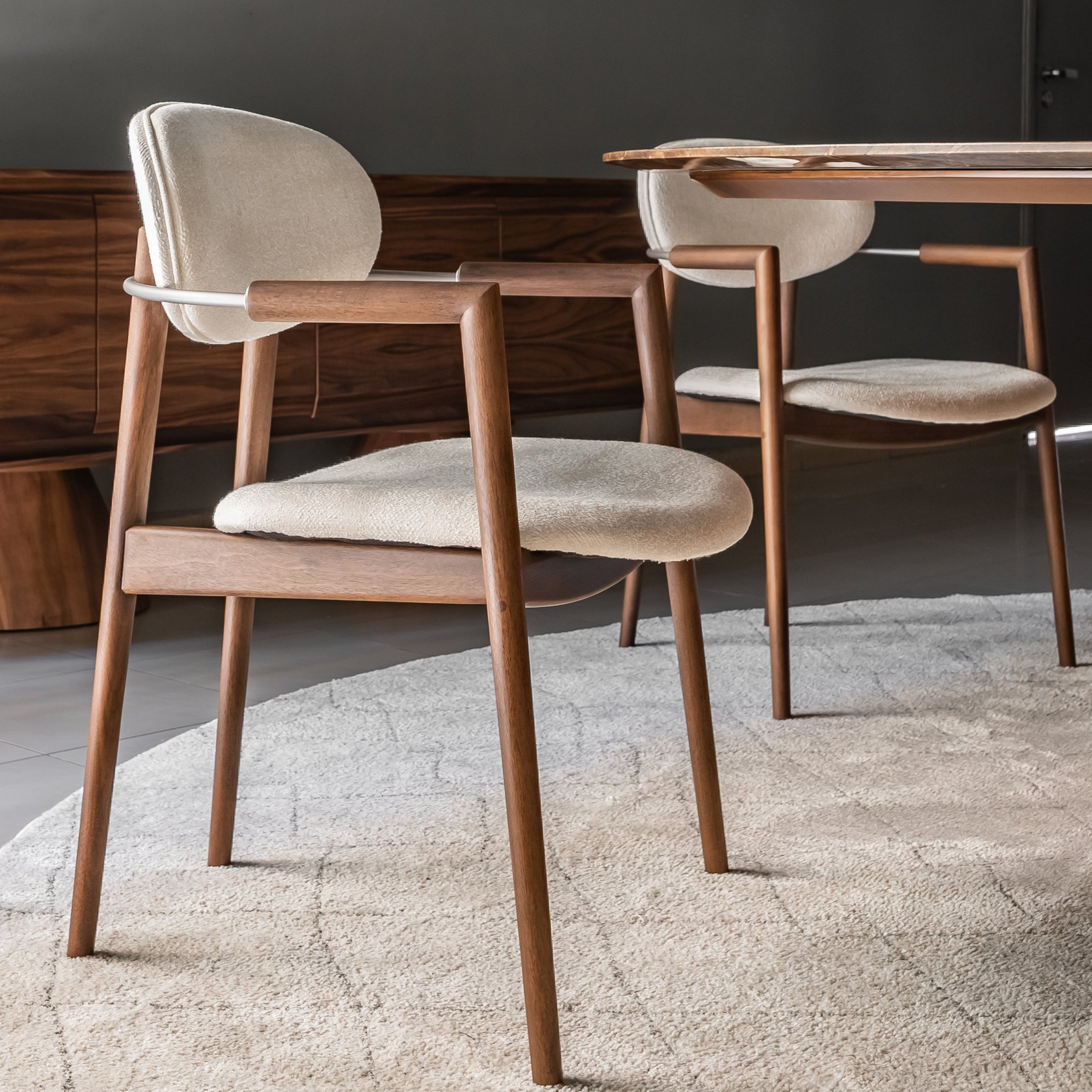Wooden chairs with beige cushions in a room with a dark wall and wooden floor.
