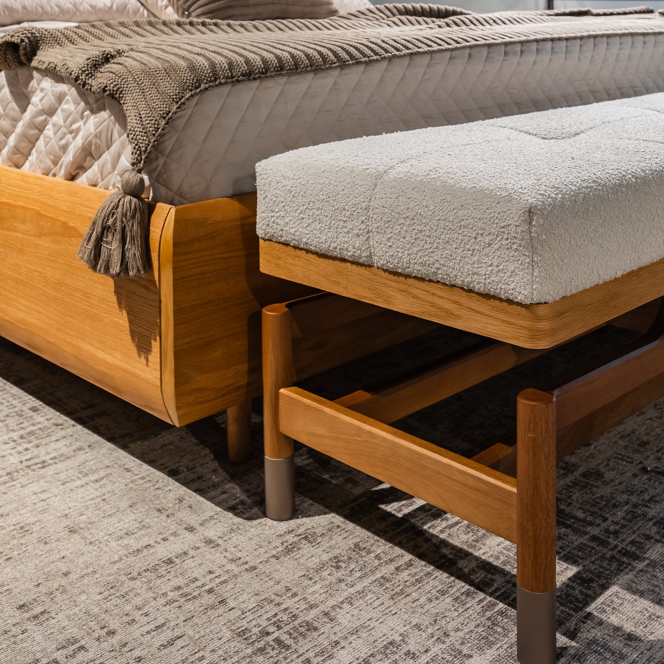 Wooden bed with beige bedding and a matching bench in a bedroom setting.