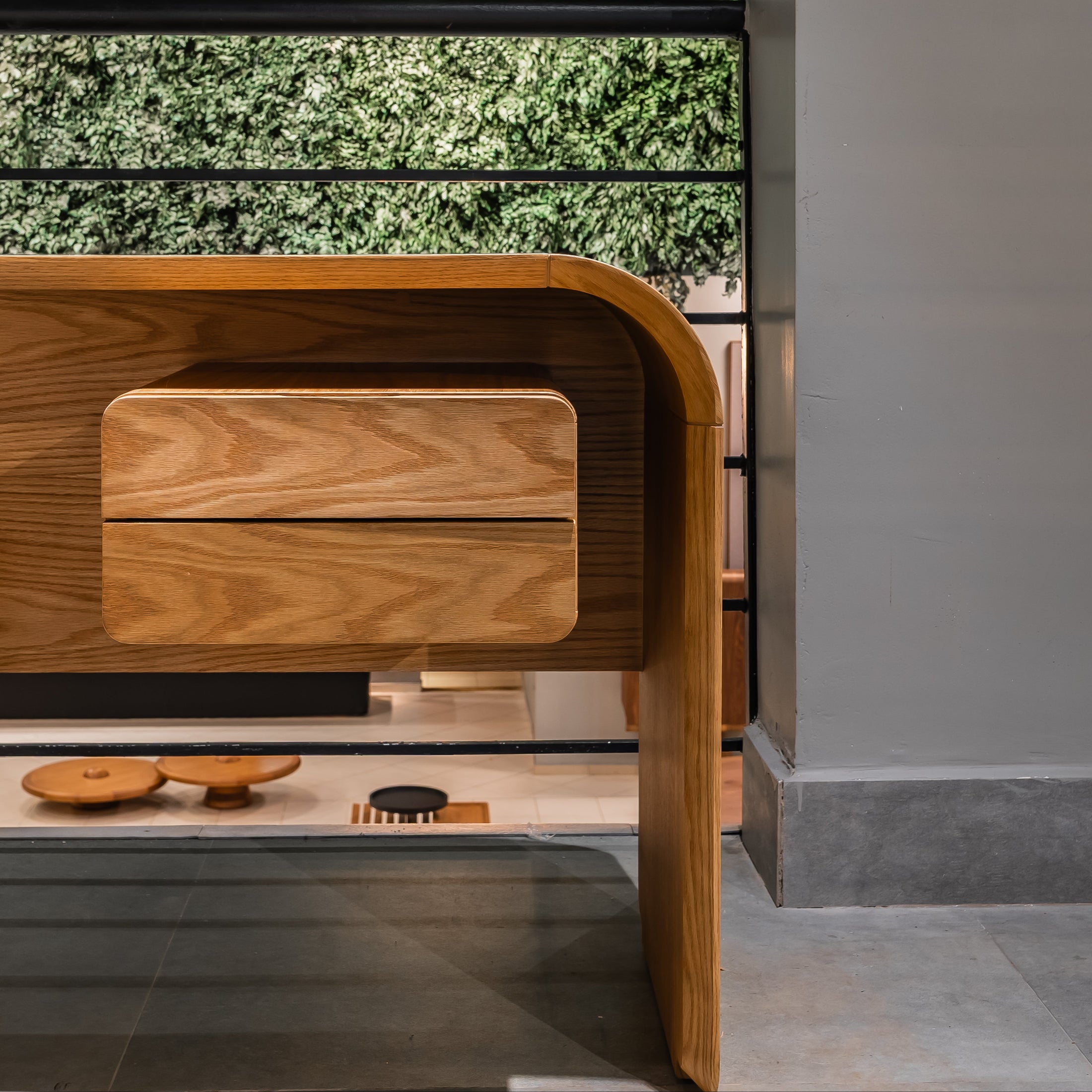 Wooden desk with a green artificial plant wall in an office setting