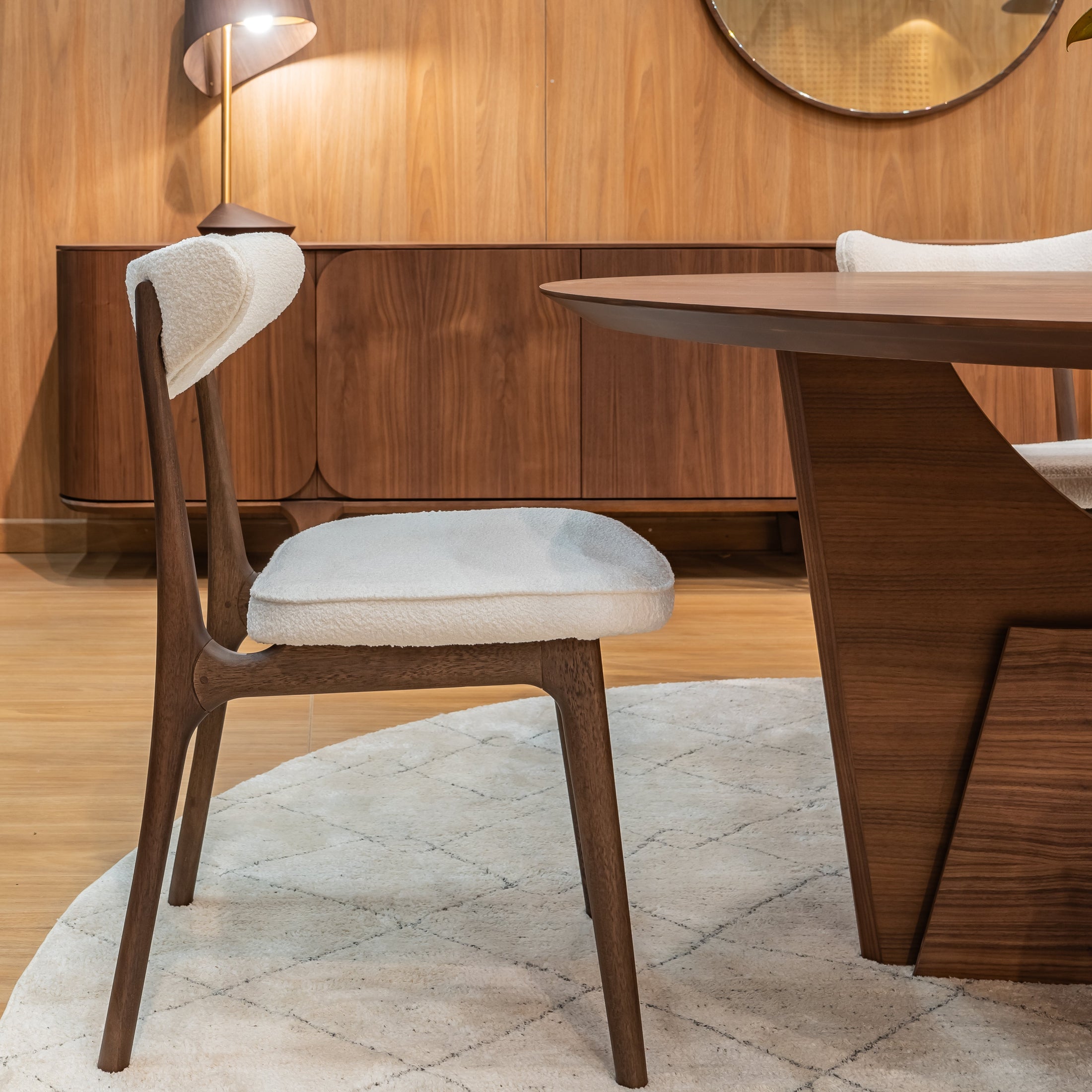 Dining area with wooden table, chairs, and wall-mounted lamp in a room with wooden walls.