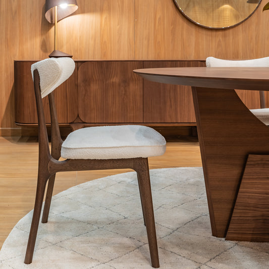 Dining area with wooden table, chairs, and wall-mounted lamp in a room with wooden walls.