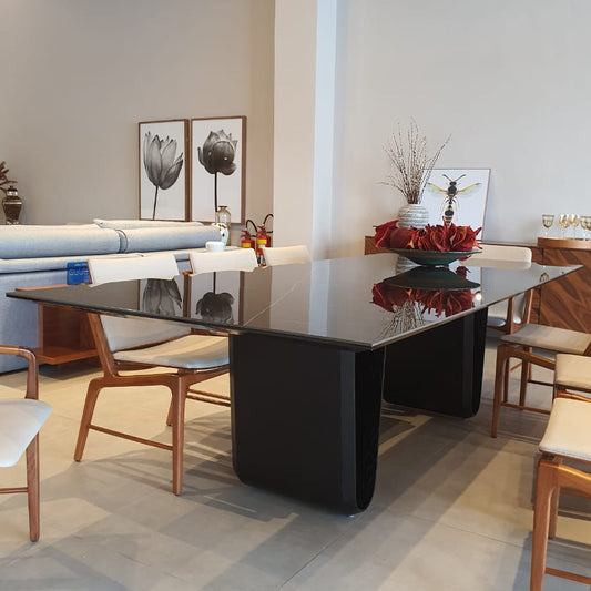 Modern dining room with a black glass table and wooden chairs.