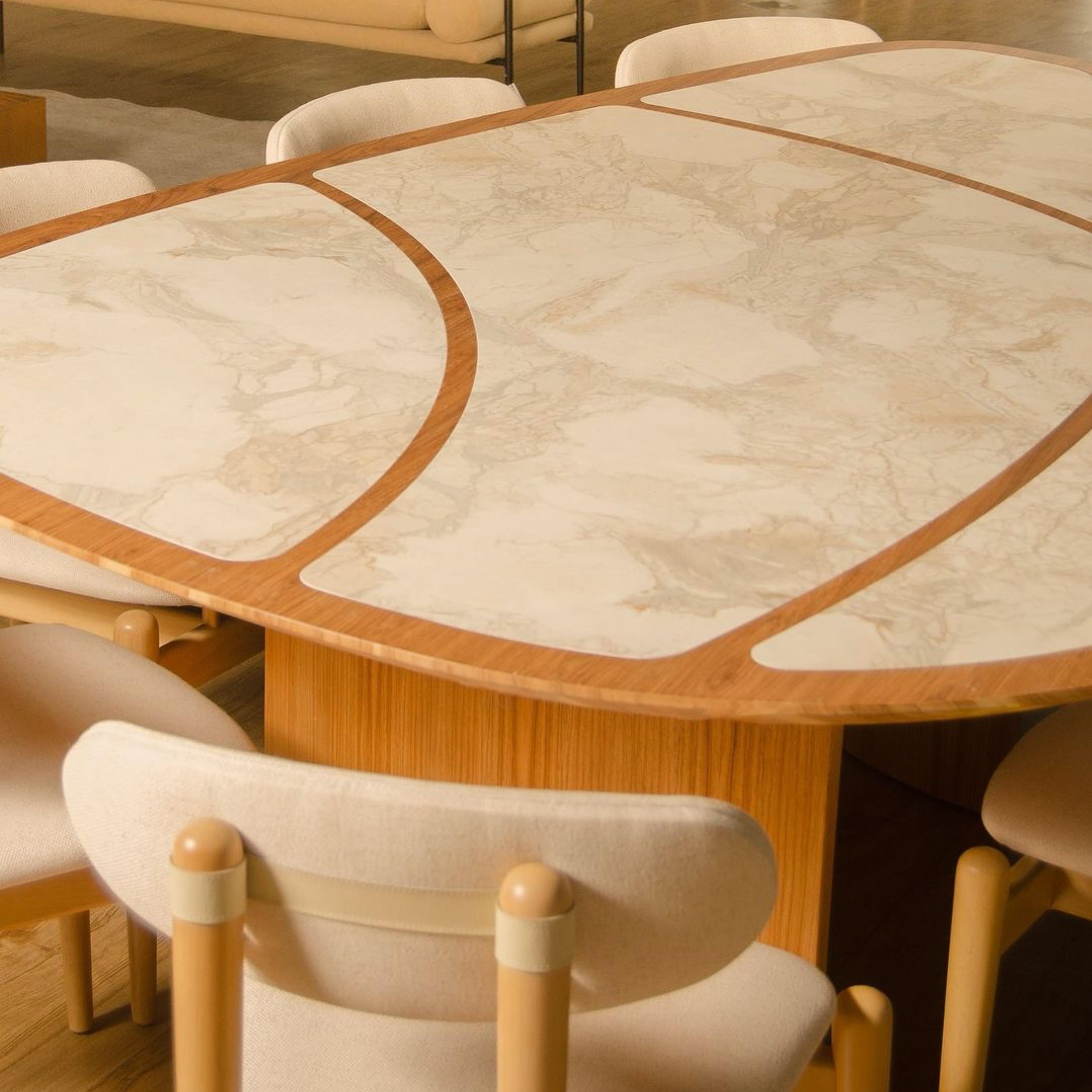 Dining table with marble-like surface and wooden frame, surrounded by chairs in a modern interior setting.