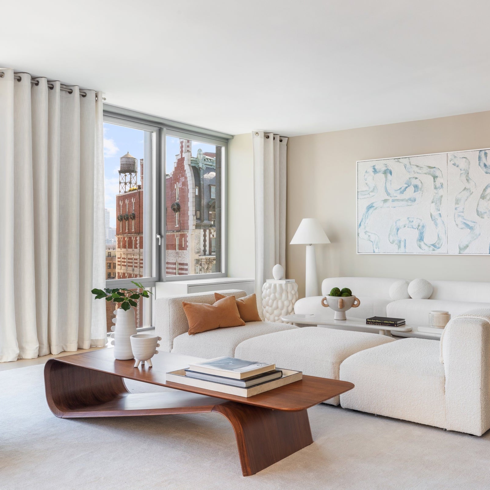 Modern living room with a white sofa, brown armchair, luxury wood coffee table and large windows.