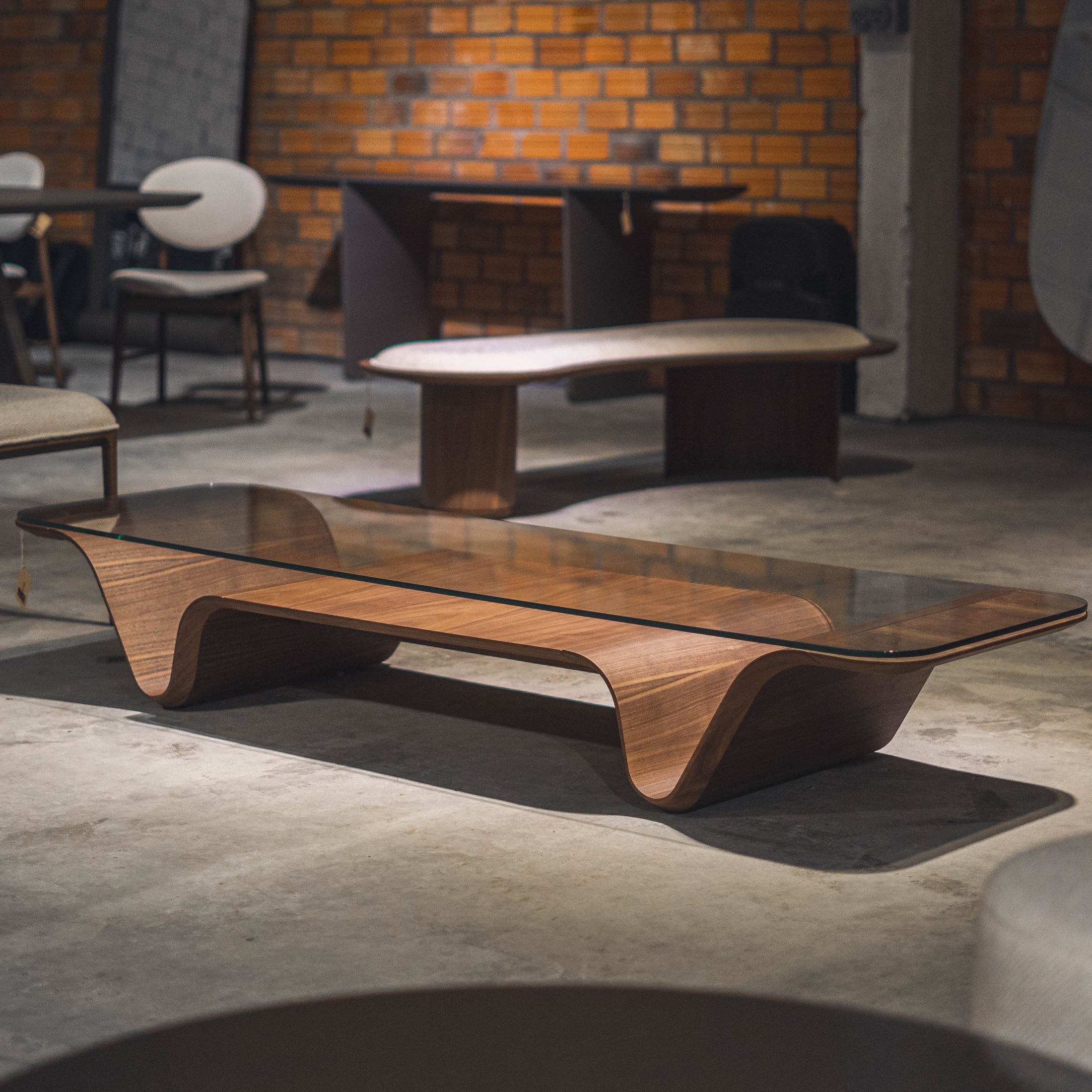 Modern wooden coffee table in a room with concrete floor and brick wall.