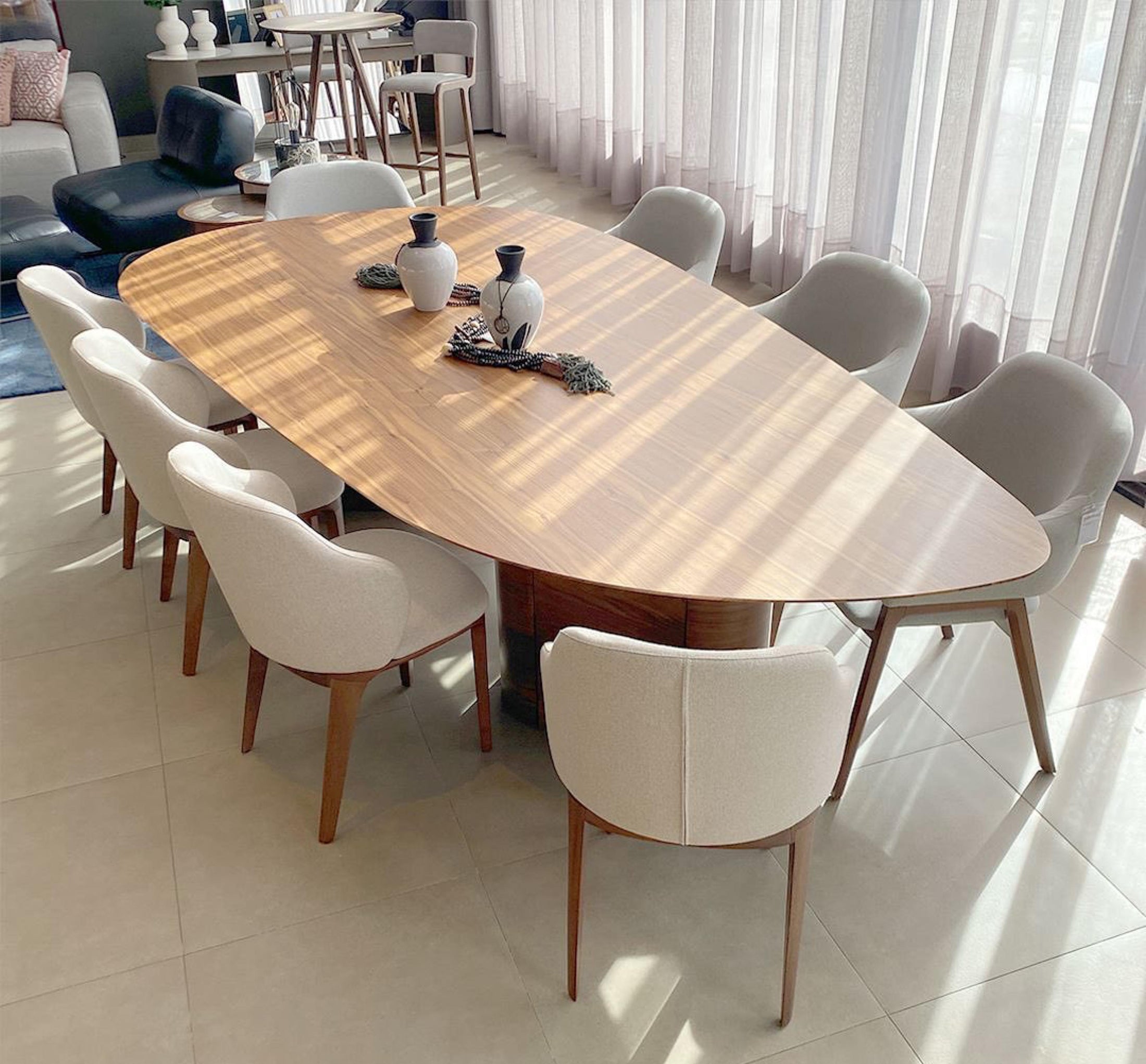 A contemporary design dining table with a smooth, oval-shaped natural oak wood tabletop, supported by two cylindrical legs.