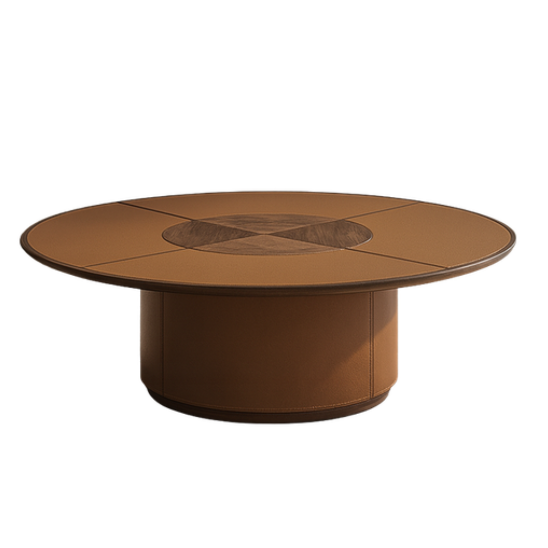 A round coffee table with a warm brown leather finish, featuring a central geometric inlay on the tabletop and a cylindrical pedestal base, shown against a plain white background.