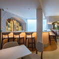 Load image into Gallery viewer, Modern restaurant interior with tables, chairs, and a bar area.
