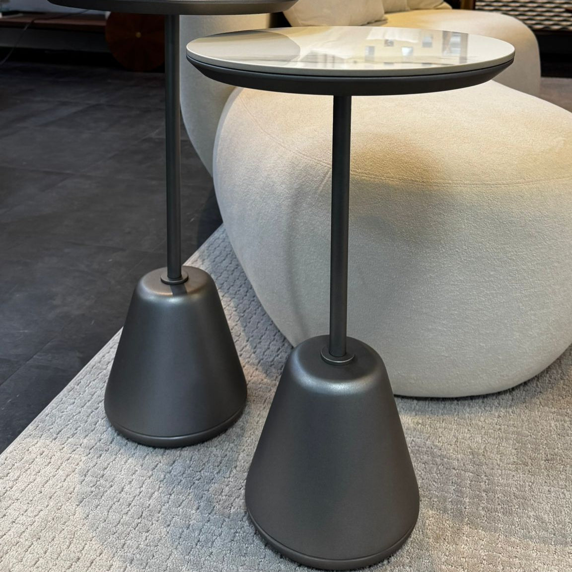 Two modern side tables with gray bases in a living room setting.