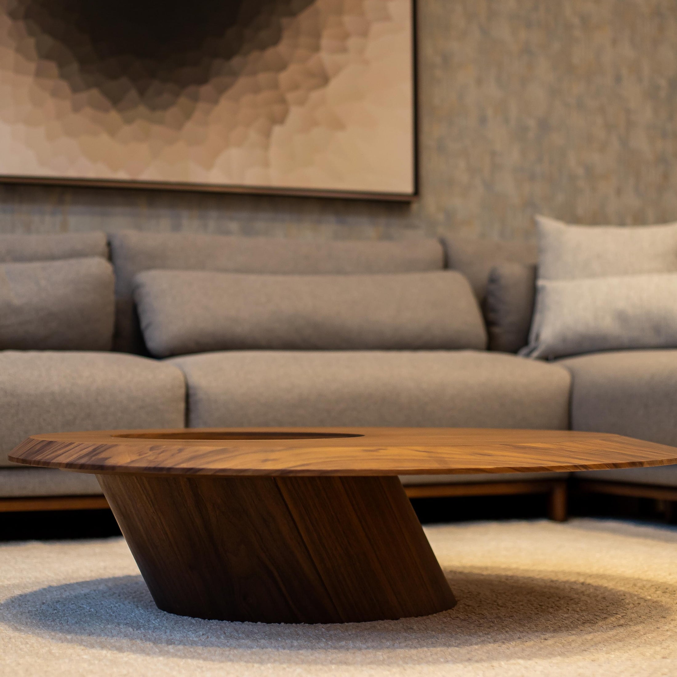 Wooden coffee table in front of a gray sofa with a textured wall in the background