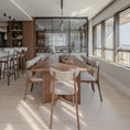 Charger l'image dans la visionneuse de la galerie, Modern dining area with wooden table and chairs in a well-lit room with large windows.
