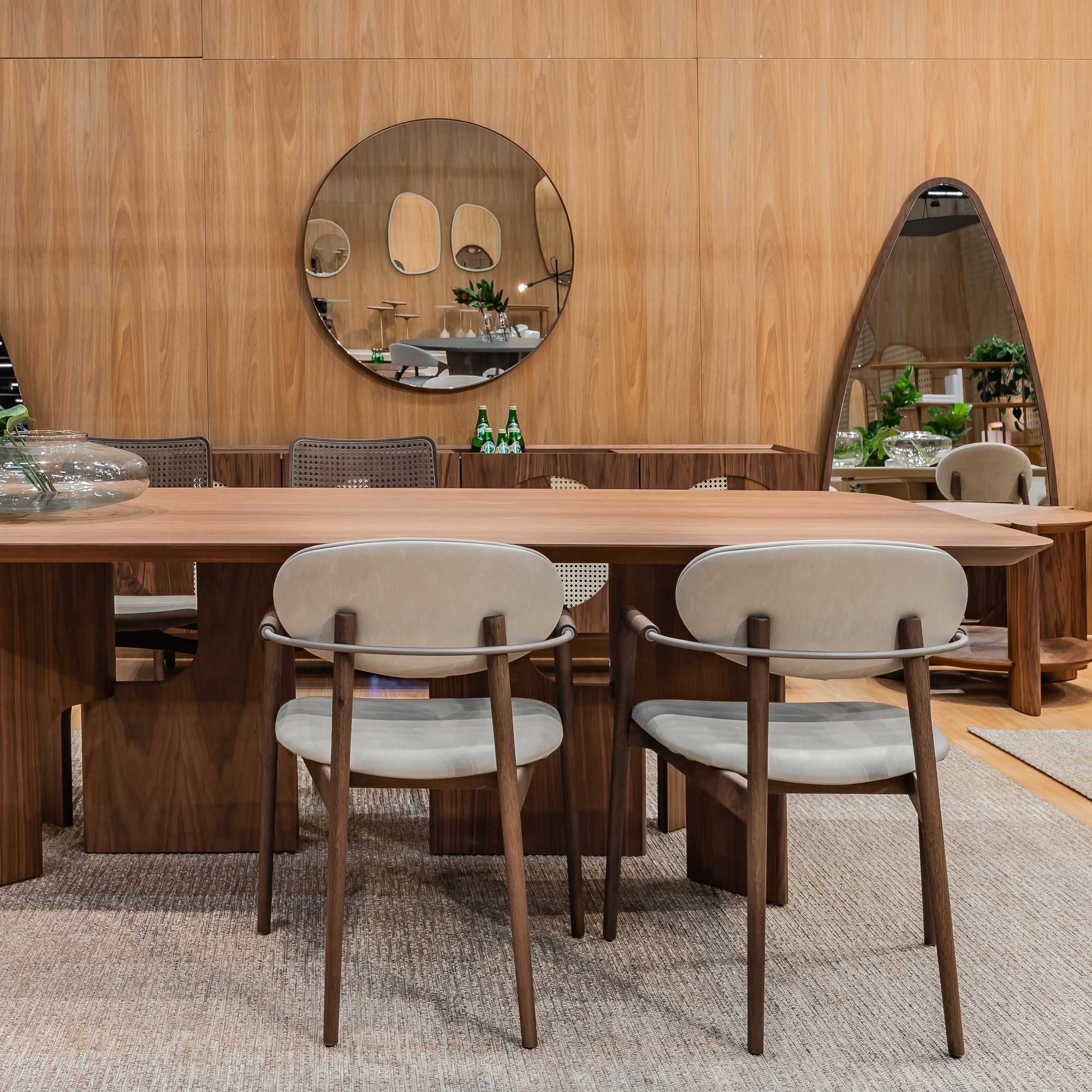 Dining area with wooden table and chairs in a room with wooden walls and mirrors.