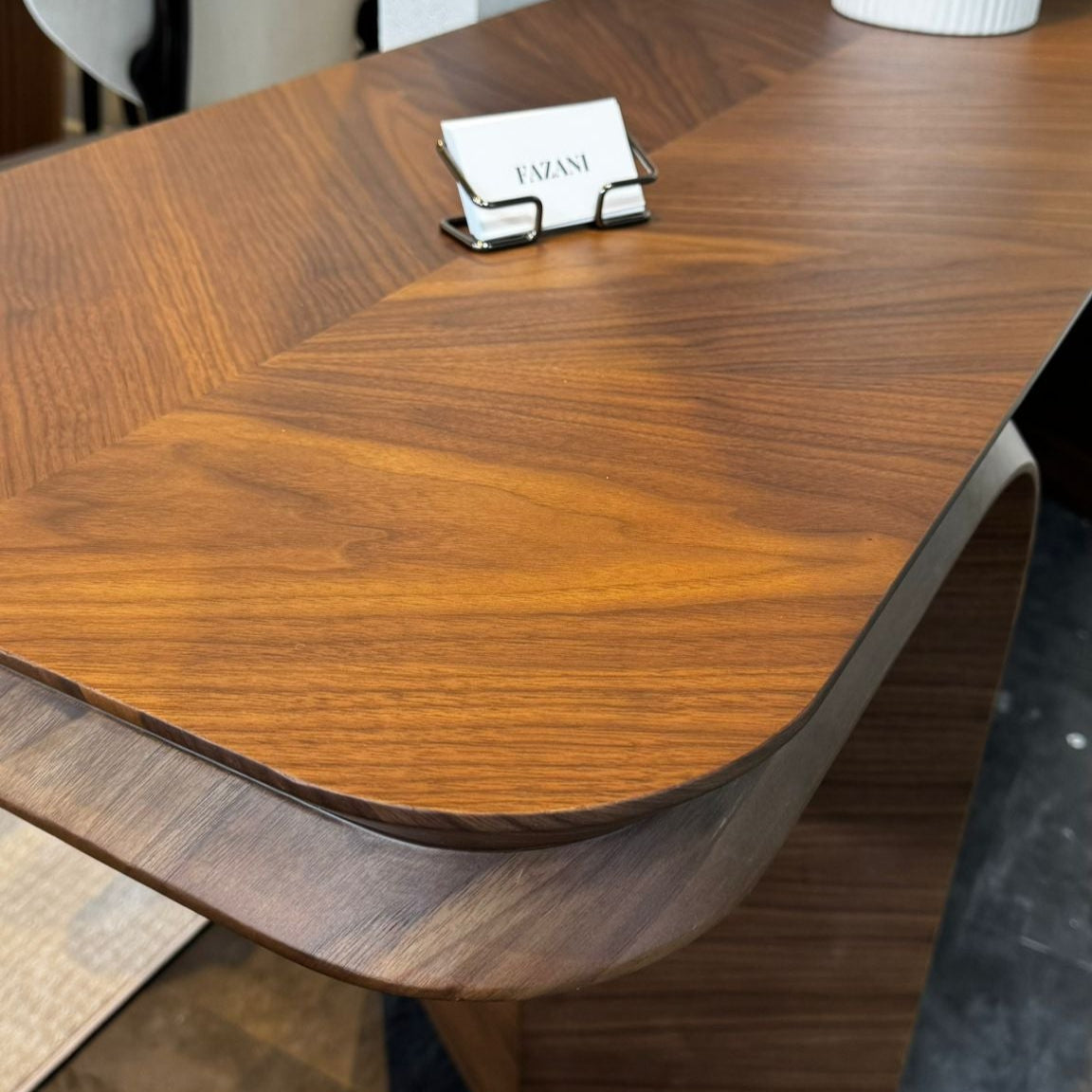 Wooden console table with a business card holder on a gray floor.