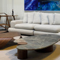 Load image into Gallery viewer, Modern living room with a large TV displaying a blue abstract painting, a white sofa, and a marble coffee table.
