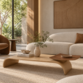 Load image into Gallery viewer, A modern low wooden coffee table with a curved sculptural base, styled in a warm, minimalist living room with a cream boucle sofa, textured rug, and natural light.
